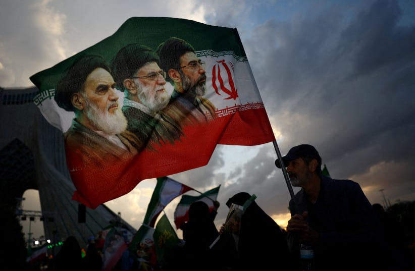 A man holds a flag with a picture of late leader of the Islamic Revolution Ayatollah Ruhollah Khomeini, late Supreme Leader of Iran Ayatollah Ali Khamenei and Iran's new Supreme Leader Mojtaba Khamenei, during a rally in Tehran, Iran, April 29, 2026.