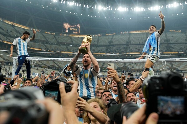Argentina's Lionel Messi celebrates with the trophy in front of the fans after winning the World Cup final soccer match between Argentina and France at the Lusail Stadium in Lusail, Qatar, Sunday, Dec. 18, 2022. (AP Photo/Martin Meissner, FIle)