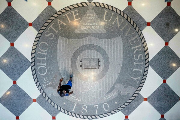 A person walks over the Ohio State University's emblem in the campus student union, May 18, 2019, in Columbus, Ohio. (AP Photo/John Minchillo, File)