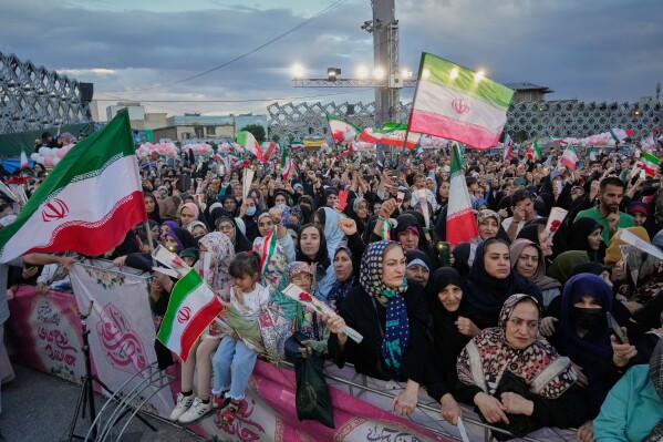 A crowd waves Iranian flags during a mass wedding ceremony for couples participating in the "Janfada" ("Sacrifice for Iran") pro-government campaign in Tehran, Iran, Monday, May 18, 2026. (AP Photo/Vahid Salemi)