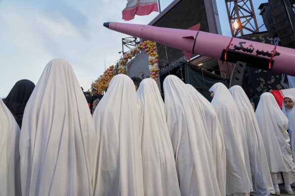 A group of girls stand beside a "Khaybar-buster" missile during a mass wedding ceremony for couples participating in the "Janfada" ("Sacrifice for Iran") pro-government campaign in Tehran, Iran, Monday, May 18, 2026. (AP Photo/Vahid Salemi)