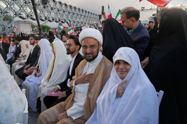 Couples sit during a mass wedding ceremony for participants in the "Janfada" ("Sacrifice for Iran") pro-government campaign in Tehran, Iran, Monday, May 18, 2026. (AP Photo/Vahid Salemi)