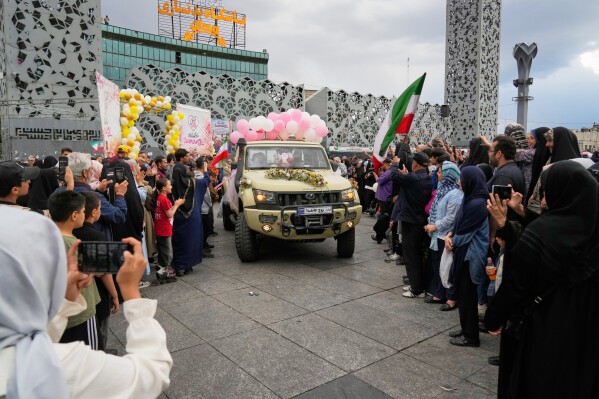 Newlyweds ride in pickup trucks during a mass wedding ceremony for couples participating in the "Janfada" ("Sacrifice for Iran") government campaign in Tehran, Iran, Monday, May 18, 2026. (AP Photo/Vahid Salemi)