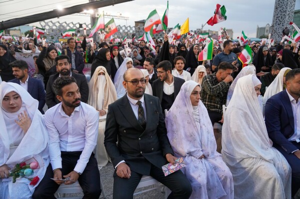 Couples sit during a mass wedding ceremony for participants in the "Janfada" ("Sacrifice for Iran") pro-government campaign in Tehran, Iran, Monday, May 18, 2026. (AP Photo/Vahid Salemi)
