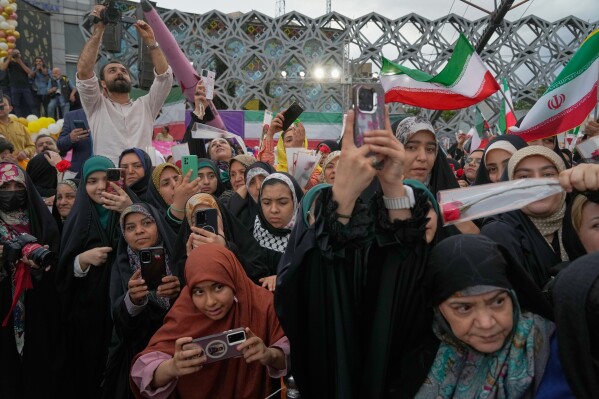 People take pictures during a mass wedding ceremony for couples participating in the "Janfada" ("Sacrifice for Iran") government campaign in Tehran, Iran, Monday, May 18, 2026. (AP Photo/Vahid Salemi)