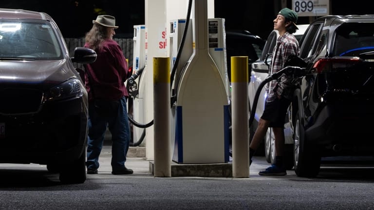 People fill up fuel tanks at a gas station on...