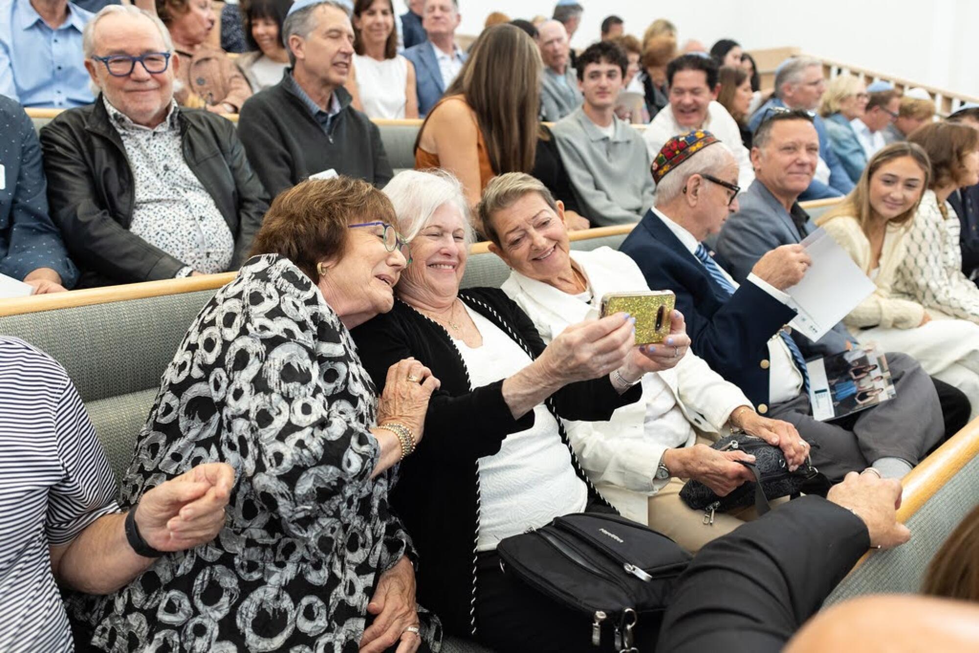 Three women lean in for a selfie in a temple pew.