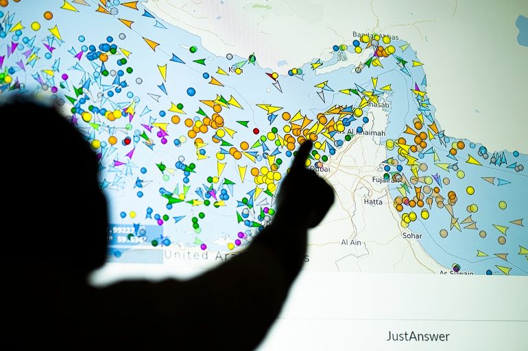 TOPSHOT - A photo illustration taken in Nicosia on May 4, 2026, shows a person in front of a large screen displaying vessel movements in the Strait of Hormuz on a ship-tracking website.