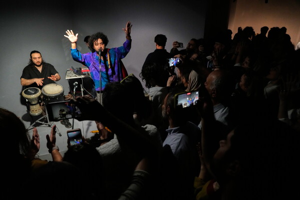 A band performs as people watch and film with their smartphones during a performance dubbed "Sounds of the South," featuring music from southern Iran, at the Tehran Museum of Contemporary Art in Tehran, Iran, Thursday, May 21, 2026. (AP Photo/Vahid Salemi)