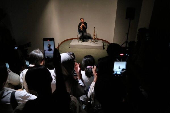 A musician performs as people film with their smartphones during a performance dubbed "Sounds of the South," featuring music from southern Iran, at the Tehran Museum of Contemporary Art in Tehran, Iran, Thursday, May 21, 2026. (AP Photo/Vahid Salemi)