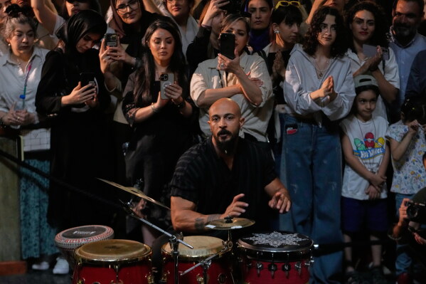 Musician Sadegh Hosseinpour plays percussion during a performance dubbed "Sounds of the South," featuring music from southern Iran, as people watch and film with their smartphones at the Tehran Museum of Contemporary Art in Tehran, Iran, Thursday, May 21, 2026. (AP Photo/Vahid Salemi)