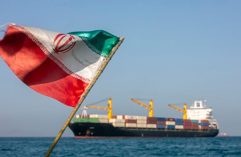 An Iranian flag flutters in the wind as ships remain anchored in the Strait of Hormuz on May 16. Negotiations between the US and Iran over opening this critical waterway have largely stalled.