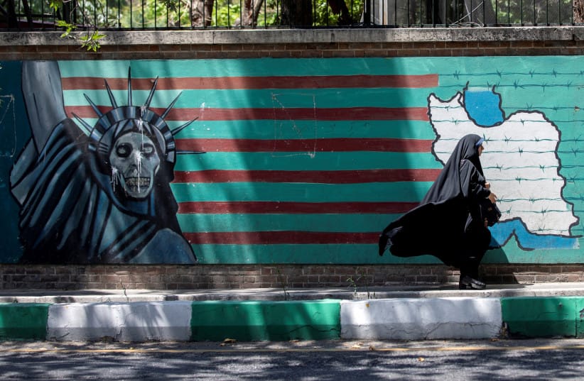 A woman walks past the mural showing U.S. flag with barbed wire and the Statue Of Liberty with skull face in Tehran, Iran June 25, 2019.