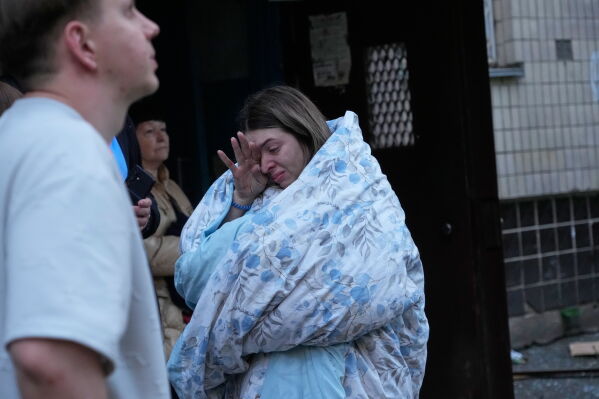 People react as they look at the site of a Russian missile strike that hit a residential building in Kyiv, Ukraine, Sunday, May 24, 2026. (AP Photo/Efrem Lukatsky)