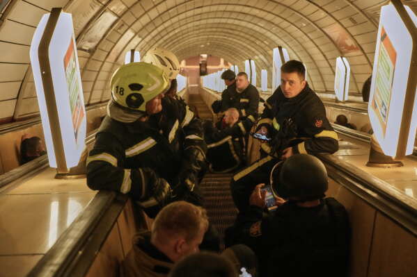 Firefighters sit on the escalator steps waiting for the end of missile strikes in a metro shelter during Russia's missile and drone attacks on capital Kyiv, Ukraine, early Sunday, May 24, 2026. (AP Photo/Efrem Lukatsky)
