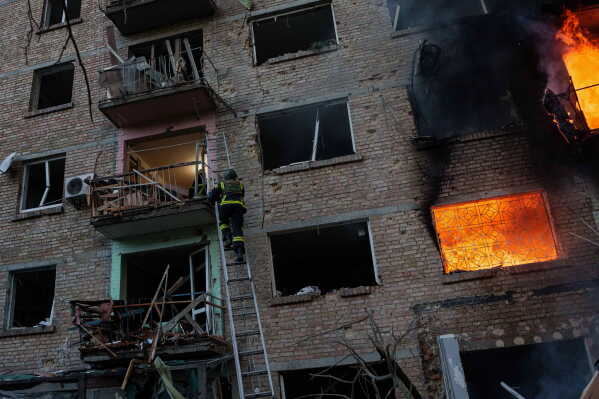 A rescue worker climbs on a ladder to help evacuate people from a residential building being destroyed after a Russian strike on Kyiv, Ukraine, Sunday, May 24, 2026. (AP Photo/Evgeniy Maloletka)