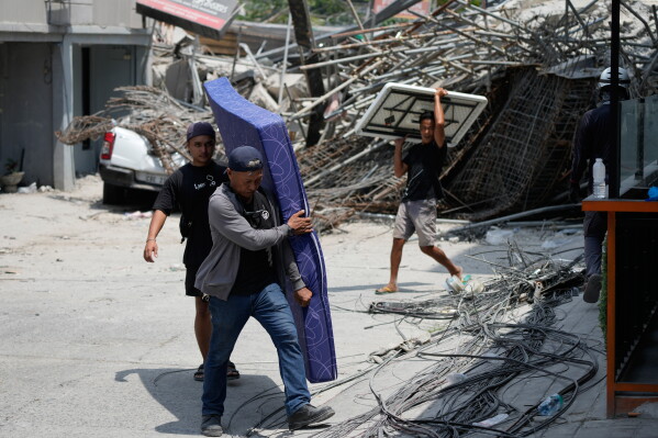 Workers carry items which they recovered from a damaged structure after a building collapsed where multiple people are believed to be trapped in Angeles city in Pampanga province, north of Manila Monday, May 25, 2026. (AP Photo/Aaron Favila)