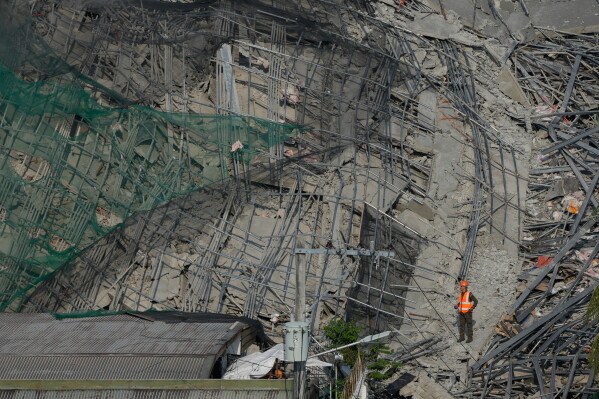 A rescuer stands on a collapsed building as search operations continue where multiple people are believed to be trapped in Angeles city in Pampanga province, north of Manila, Philippines, Monday, May 25, 2026. (AP Photo/Aaron Favila)