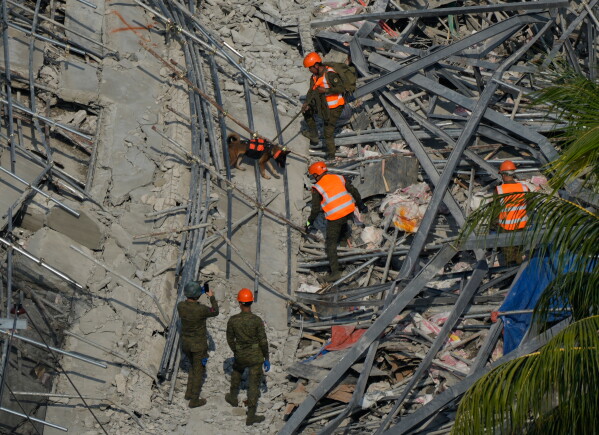 A K-9 joins rescuers as they continue search operations at a collapsed building where multiple people are believed to be trapped in Angeles city in Pampanga province, north of Manila, Philippines, Monday, May 25, 2026. (AP Photo/Aaron Favila)