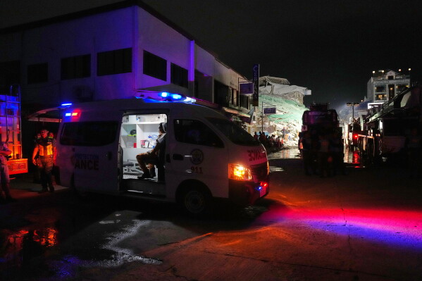 An ambulance awaits as rescue workers continue the search at a collapsed building where multiple people are believed to be trapped in Angeles city in Pampanga province, north of Manila Sunday, May 24, 2026. (AP Photo/Aaron Favila)