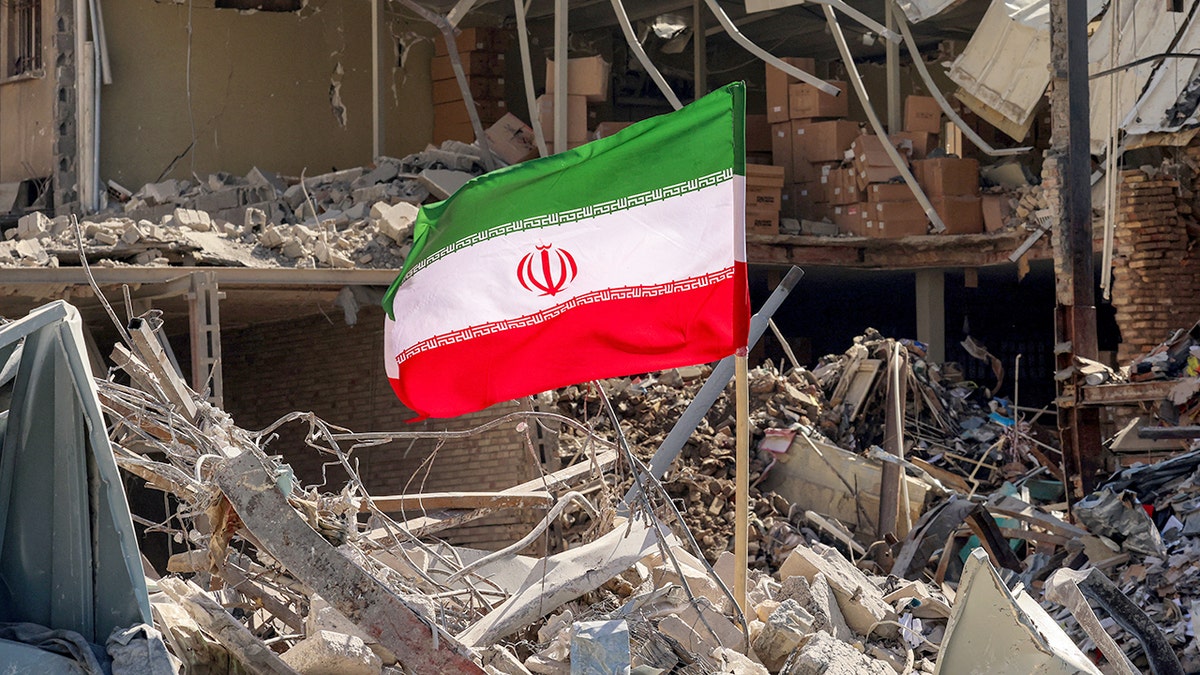 Iranian flag placed amid rubble next to destroyed residential building in Tehran