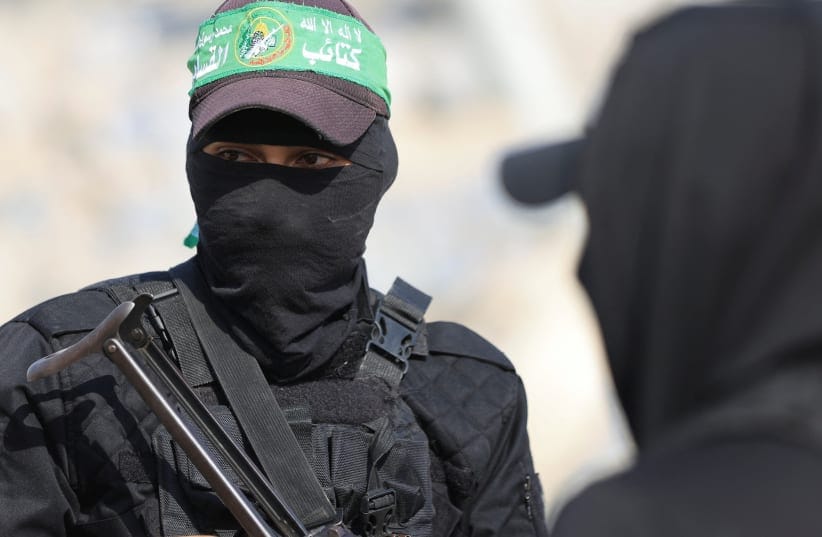 Hamas members look on as they escort members of the Red Cross towards an area within the yellow line, in Gaza City, November 12, 2025.  