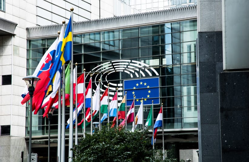 An illustrative image of a number of European Union member states' flags leading up to the EU flag at the European Parliament headquarters in Brussels, Belgium.
