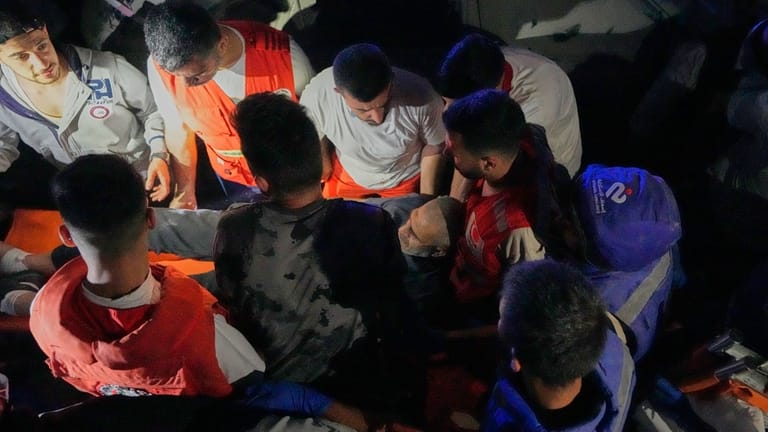 Rescue workers carry an injured man from a destroyed apartment...