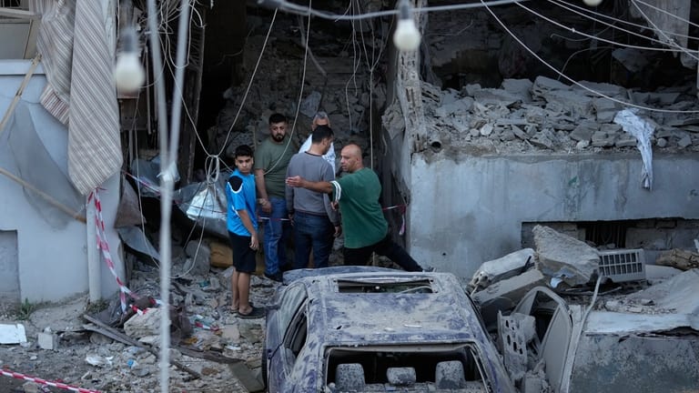 People gather outside a destroyed apartment that was hit in...