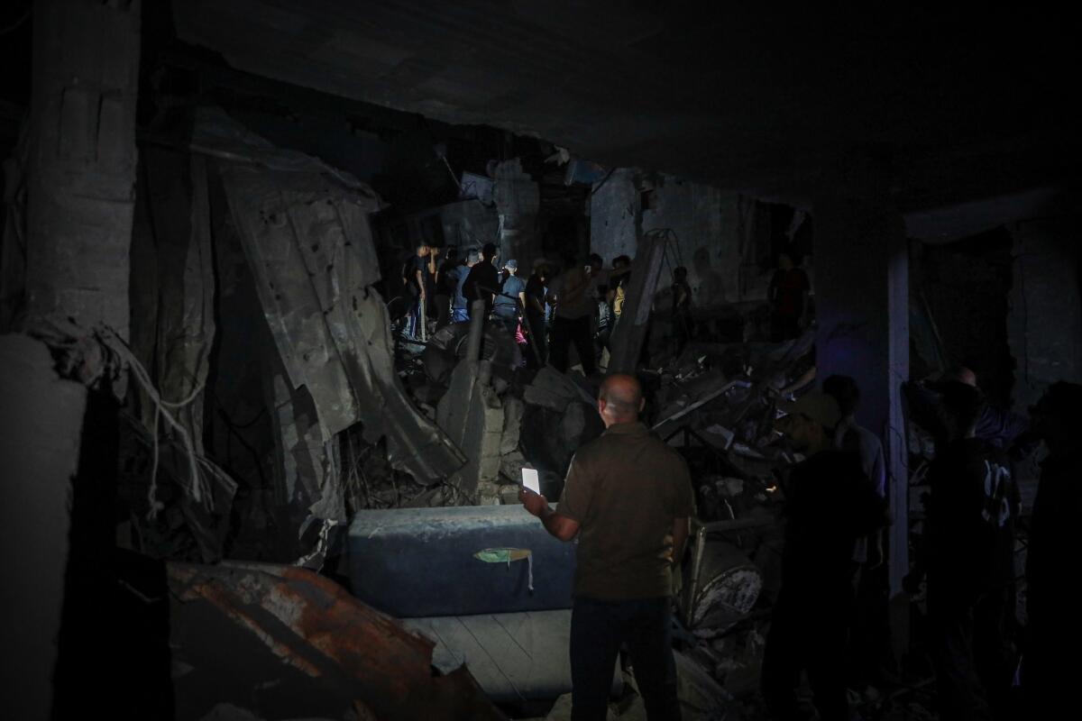 Palestinians conduct search-and-rescue operations amid the rubble of damaged residential buildings