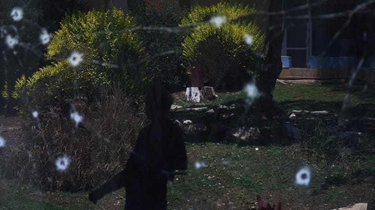 A person walks past the site struck by a rocket...