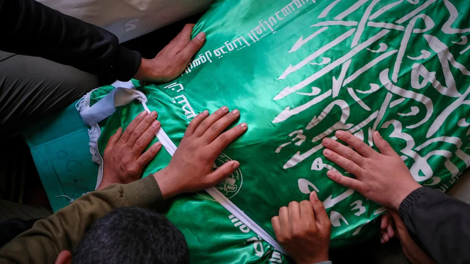 Palestinians place their hands on the body of Izz al-Din al-Haddad at his funeral.<span> Credit: AP</span>