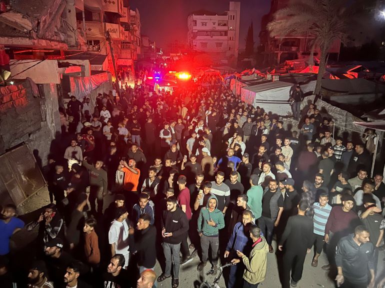 People gather around a residential apartment as a fire burns after Israeli shelling