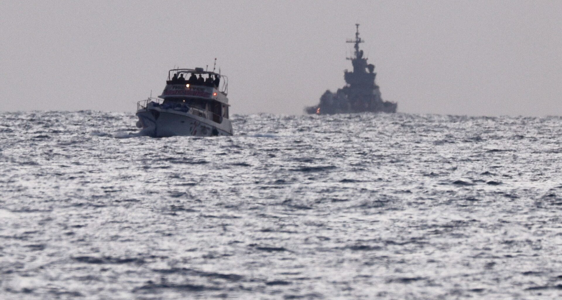 Israeli soldiers are seen on a vessel bearing symbols of the Global Sumud Flotilla, with an Israeli military ship behind it, as seen from Ashdod