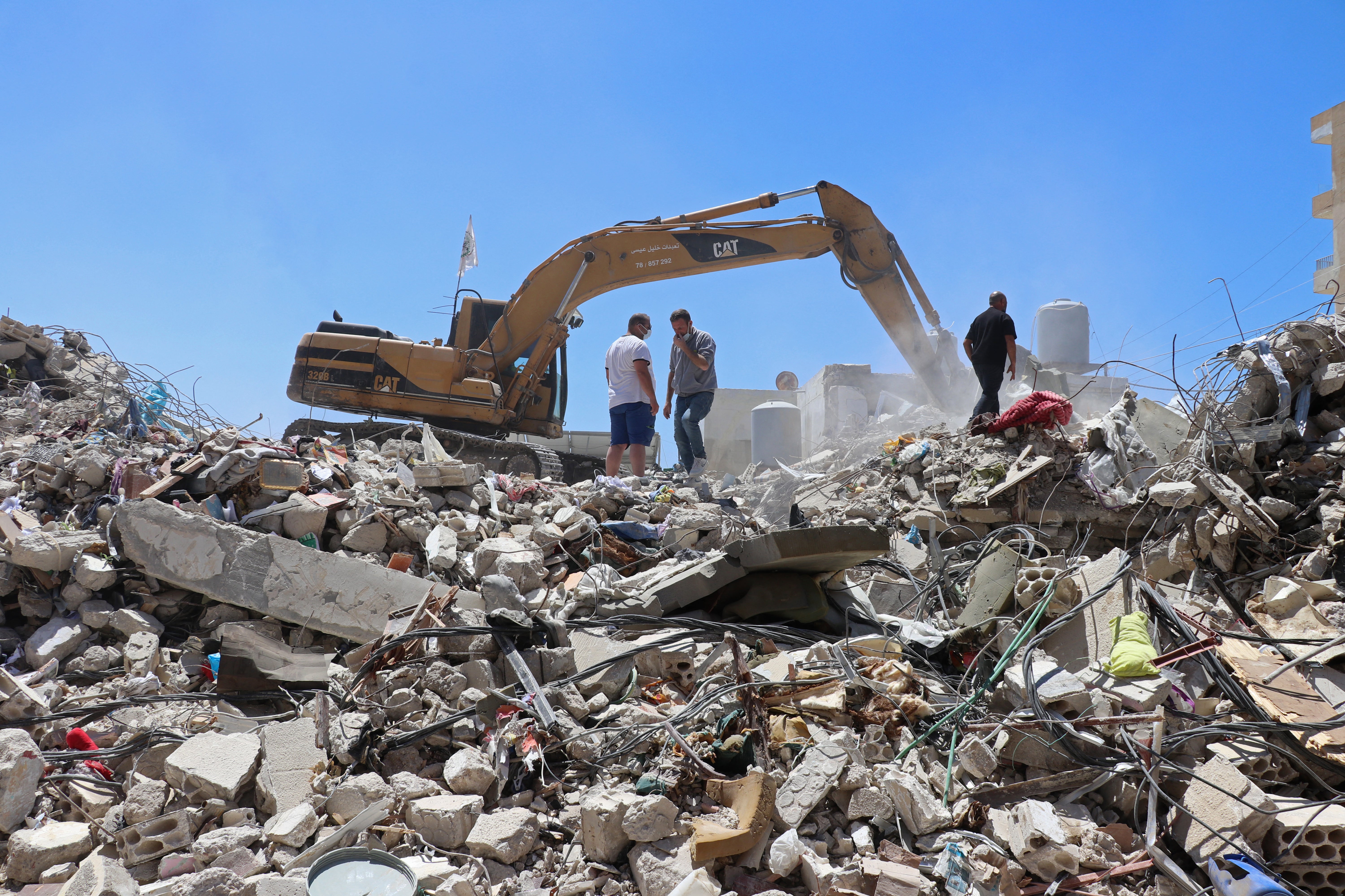 Resident Mohamad Ali Hijazi stands next to an excavator clearing the rubble of destroyed buildings at a residential area in Tyre