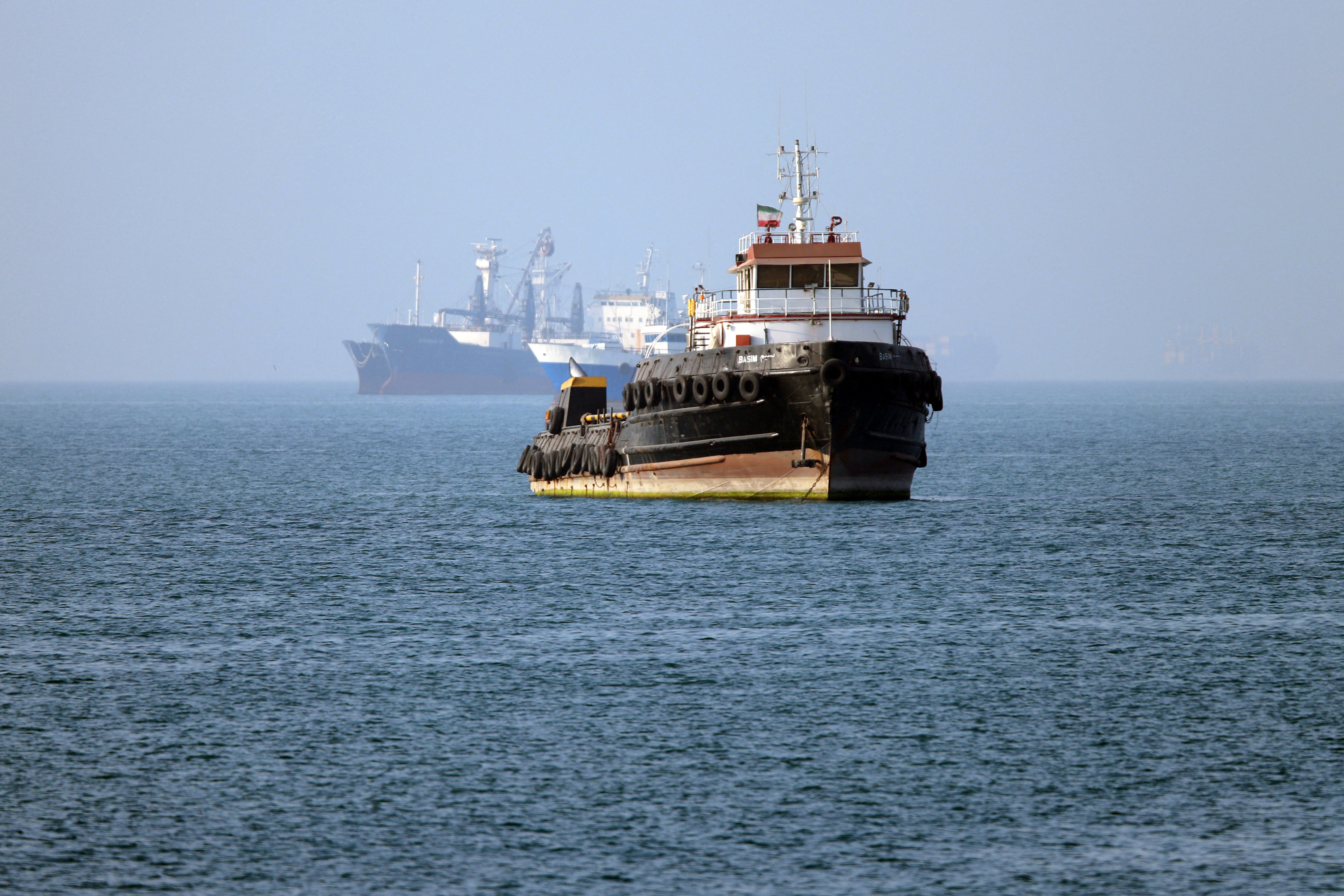 The Iran-flagged tugboat Basim sails near a ship anchored in the Strait of Hormuz