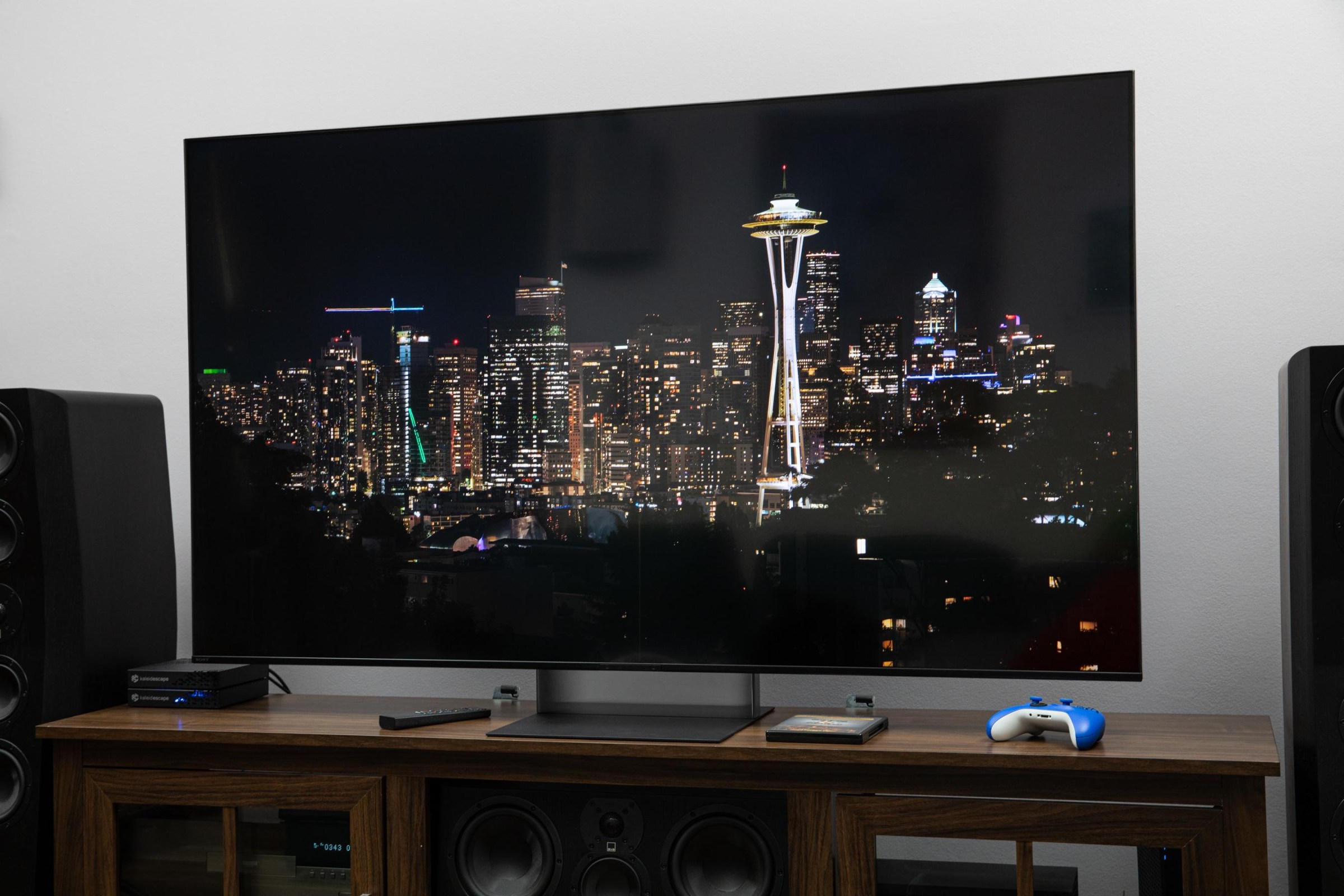 The Sony Bravia 7 II RGB LED TV on a dark wooden credenza displaying a city nighttime scene.