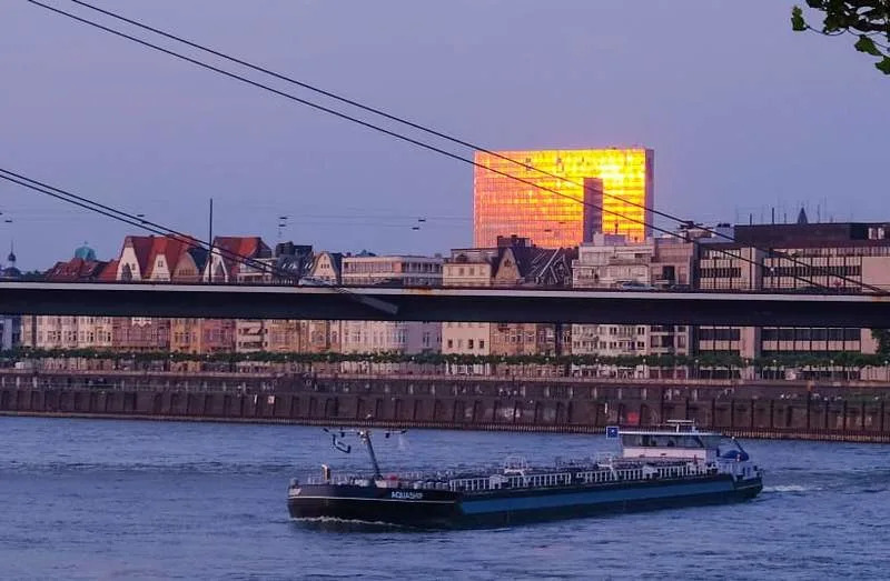 A barge maneuvers river Rhine with the Duesseldorf city skyline behind it as the sun sets in western Germany on May 28, 2018. (credit: PATRIK STOLLARZ/AFP via Getty Images)
