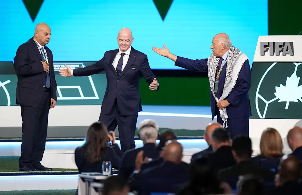 Palestinian Football Association President Jibril Rajoub, right, walks away from FIFA President Gianni Infantino, center, after refusing to stand together with Israel Football Association Vice-President Basim Sheikh Suliman, left (AP)