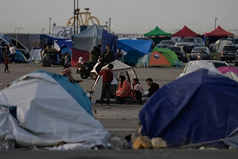 People who fled Israeli strikes in Dahiyeh sit outside tents used as shelter in Beirut, 15 April, 2026