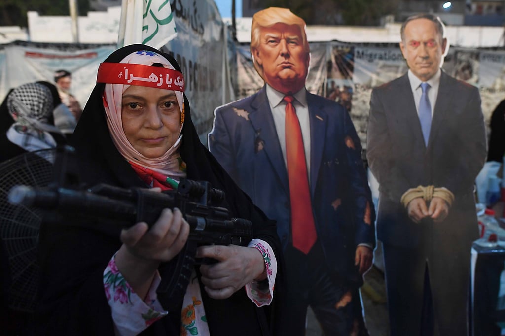 A woman holds a rifle next to cardboard cut-outs depicting US President Trump (centre) and Israeli Prime Minister Benjamin Netanyahu at a rally in Karachi, Pakistan, on May 3. Photo: EPA