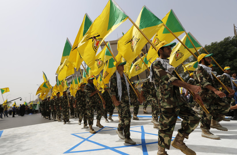 Iraqi Shi'ite Muslim men from the Iranian-backed group Kataib Hezbollah wave the party's flags as they walk along a street painted in the colours of the Israeli flag during a parade marking the annual Quds Day, or Jerusalem Day, on the last Friday of the Muslim holy month of Ramadan, in Baghdad