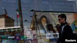 A mural depicting the late leader of the Islamic Revolution, Ayatollah Ruhollah Khomeini, is reflected in a bookshop window display in Tehran on May 12.