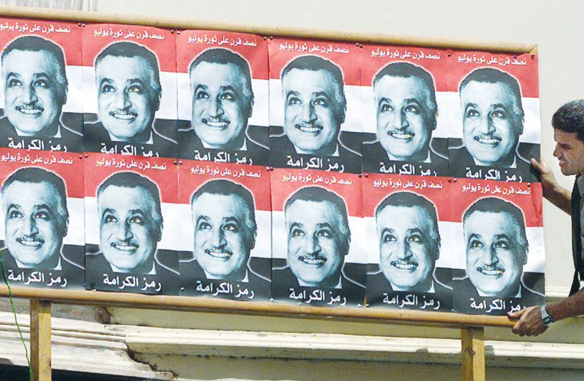 A MAN adjusts a billboard with pictures of former president Gamal Abdel Nasser, in Cairo, July 2002, the 50th anniversary of the revolution when the Free Officers, led by Nasser, seized power from the monarchy.