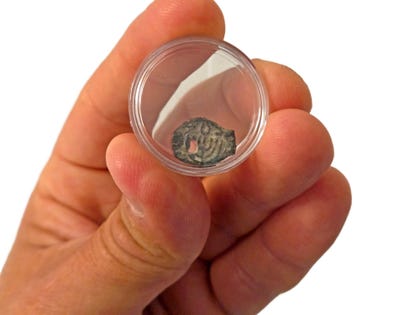 Holding up one of the coins, which were recovered in a complex international operation by Israeli and U.S. authorities.