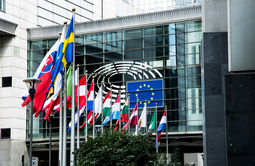 An illustrative image of a number of European Union member states' flags leading up to the EU flag at the European Parliament headquarters in Brussels, Belgium.