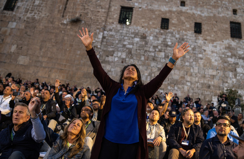 A woman raises her hands during a mass prayer with the one thousand Christian Pastors on the southern steps of the Western Wall in Jerusalem on December 4, 2025.