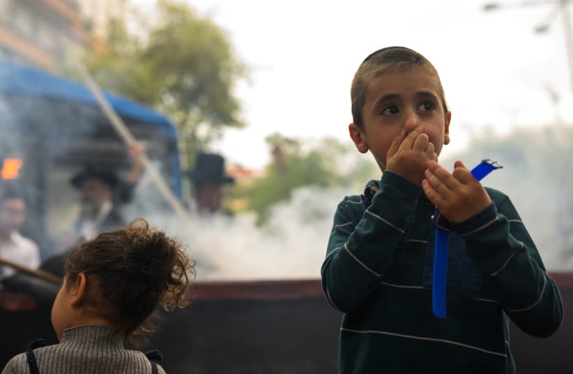 A child covers his nose and reacts while participating in the ''biur chametz,'' a ritual burning of chametz.