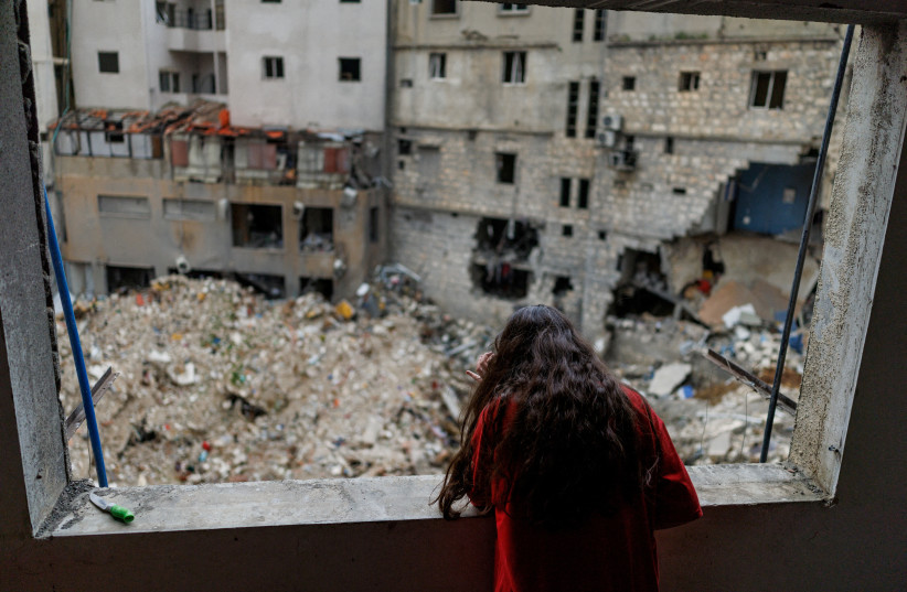 Alaa Dahnoun, 12, who said she survived an Israeli strike that forced her to flee with her parents to Beirut, looks out through her apartment's damaged window after a 10-day ceasefire between Lebanon and Israel went into effect, in Nabatieh, Lebanon, April 18, 2026.