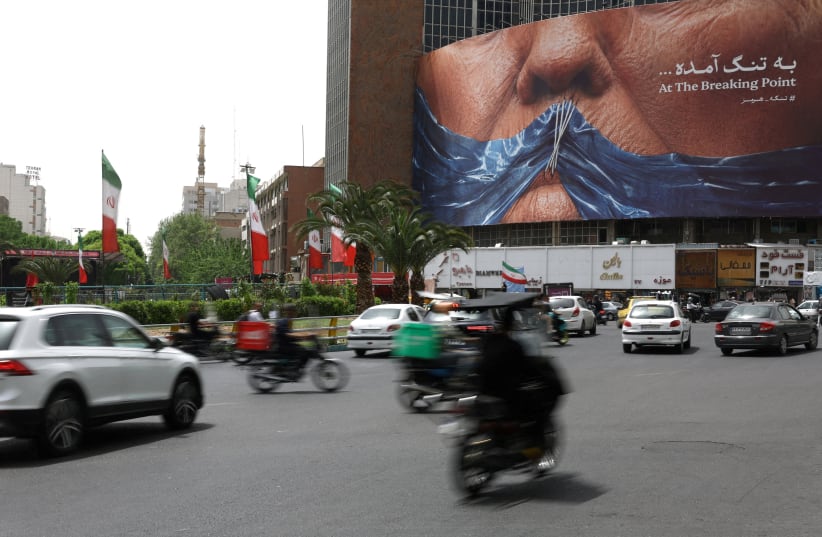 People drive past an anti-US billboard depicting U.S. President Donald Trump and the Strait of Hormuz, in Tehran, Iran, May 4, 2026. 